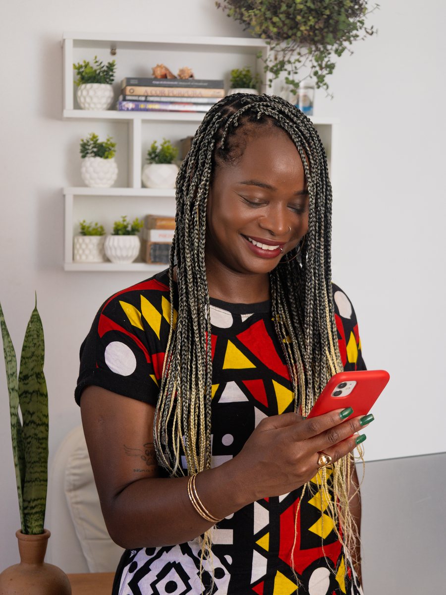 Priscila sorrindo, com o celular na mão, no consultório