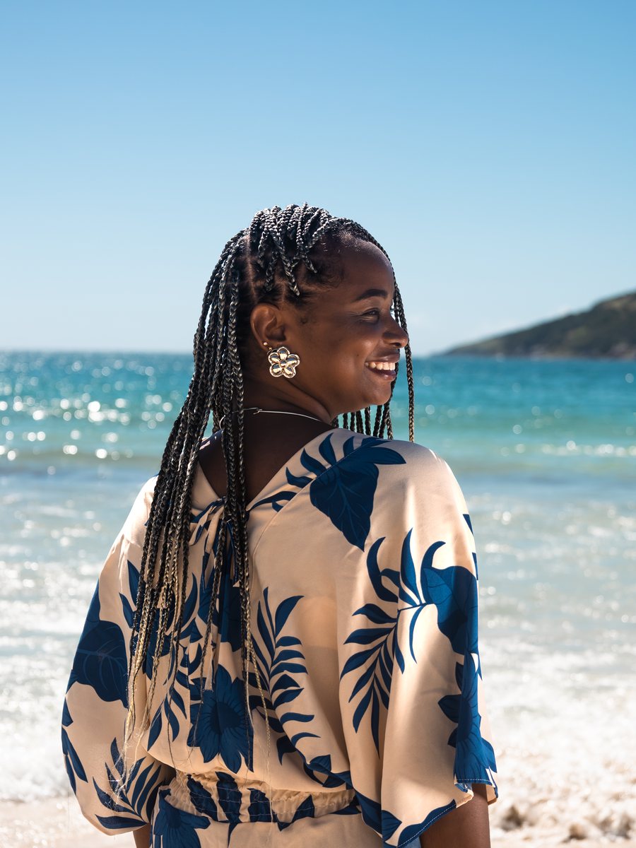 Priscila na praia, olhando por sobre o ombro para o mar